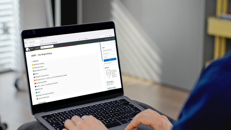 An open laptop, hands touching the keyboard. The screen shows a website with the heading "GRIPS - Uni Regensburg".