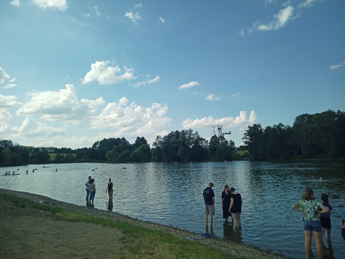Menschen stehen mit hochgekrempelten Hosen und Röcken im See. (öffnet Vergrößerung des Bildes)