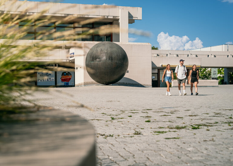 Studierende gehen über das Forum am Campus der Universität Regensburg. 