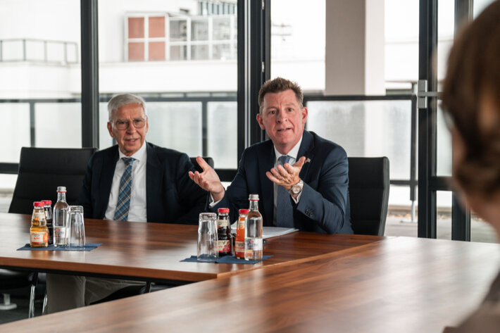 Zwei Männer in Anzügen im Gespräch in einem Konferenzraum (öffnet Vergrößerung des Bildes)