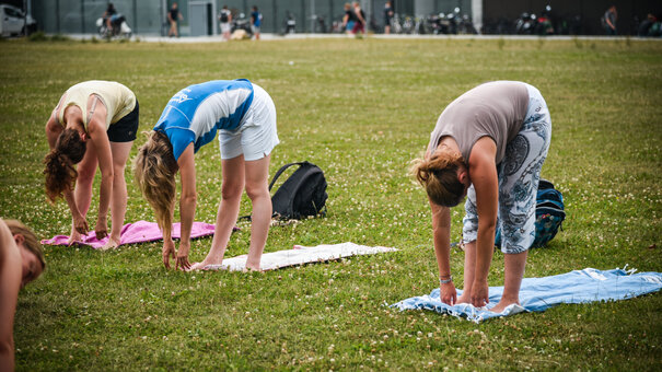 Drei Personen, die Yoga auf der Campuswiese der Uni Regensburg machen