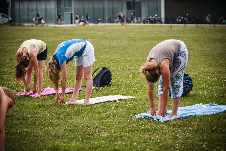 Drei Personen, die Yoga auf der Campuswiese der Uni Regensburg machen