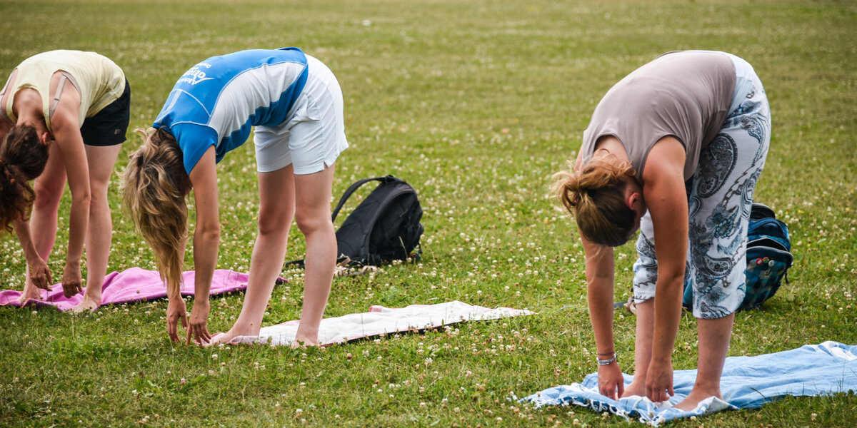 Drei Personen, die Yoga auf der Campuswiese der Uni Regensburg machen
