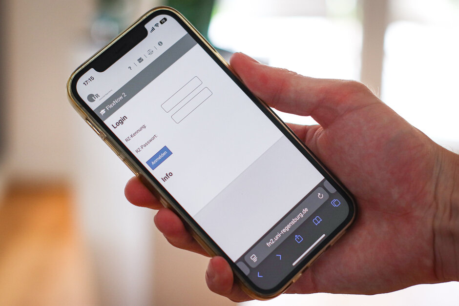 Eine Hand hält ein Smartphone. Auf dem Bildschirm ist eine Anmelde-Maske zu sehen.