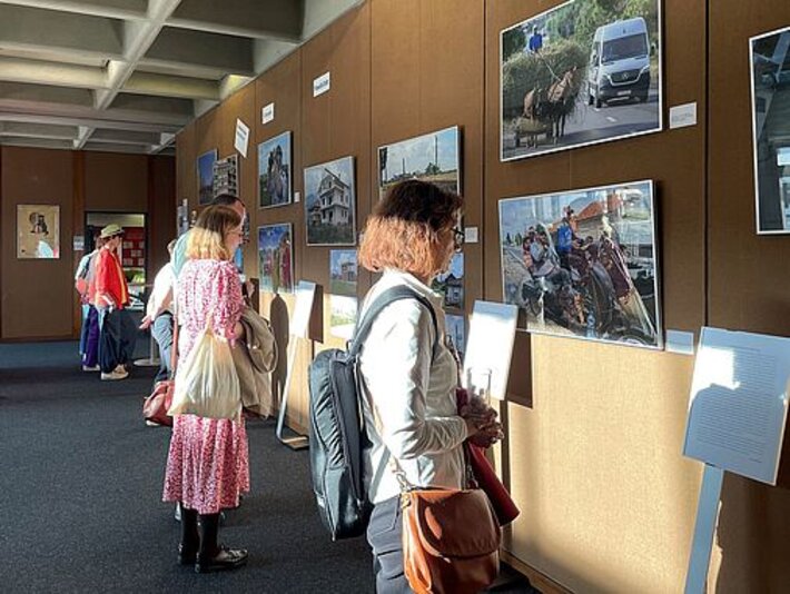 Menschen betrachten Bilder der Ausstellung. (öffnet Vergrößerung des Bildes)
