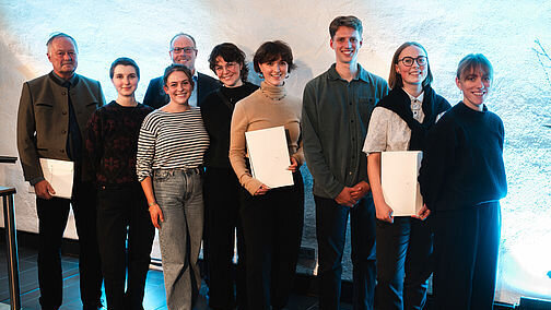 Eine Gruppe von neun Personen lächelt in die Kamera. Drei halten Urkundenmappen in der Hand.