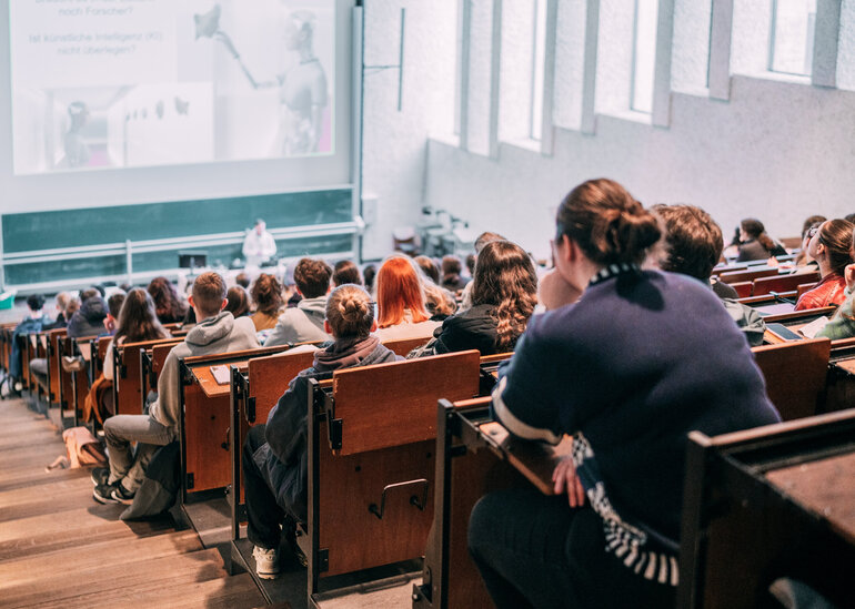 Vorlesung in einem gut besuchten Hörsaal mit Tageslicht im Gebäudeteil Recht und Wirtschaft