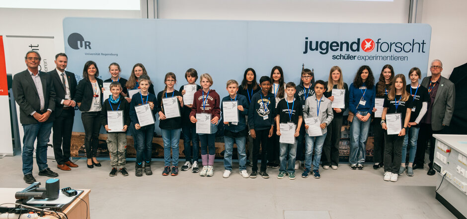Viele Jugendliche stehen als Gruppenbild zusammen und zeigen ihre Urkunden in die Kamera. (öffnet Vergrößerung des Bildes)