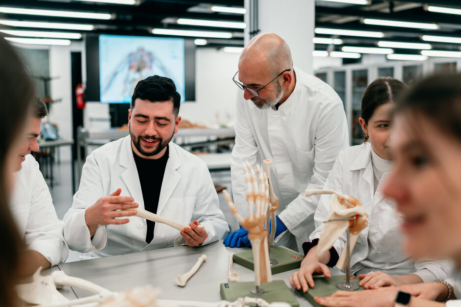 Ein Professor im Gespräch mit einem Studierenden, der anatomische Modelle betrachtet.