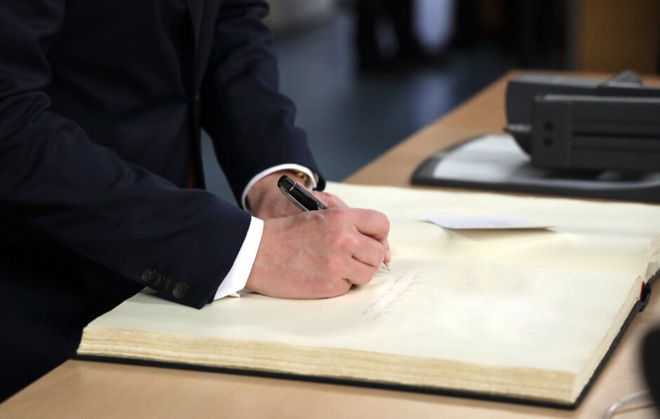 Ein Hand schreibt mit einem hochwertigen Füllfederhalter ein paar Zeilen in ein großformatiges Gästebuch.