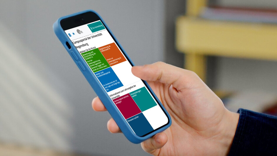 One hand holds a smartphone with a blue case. The display shows the homepage of the student portal.