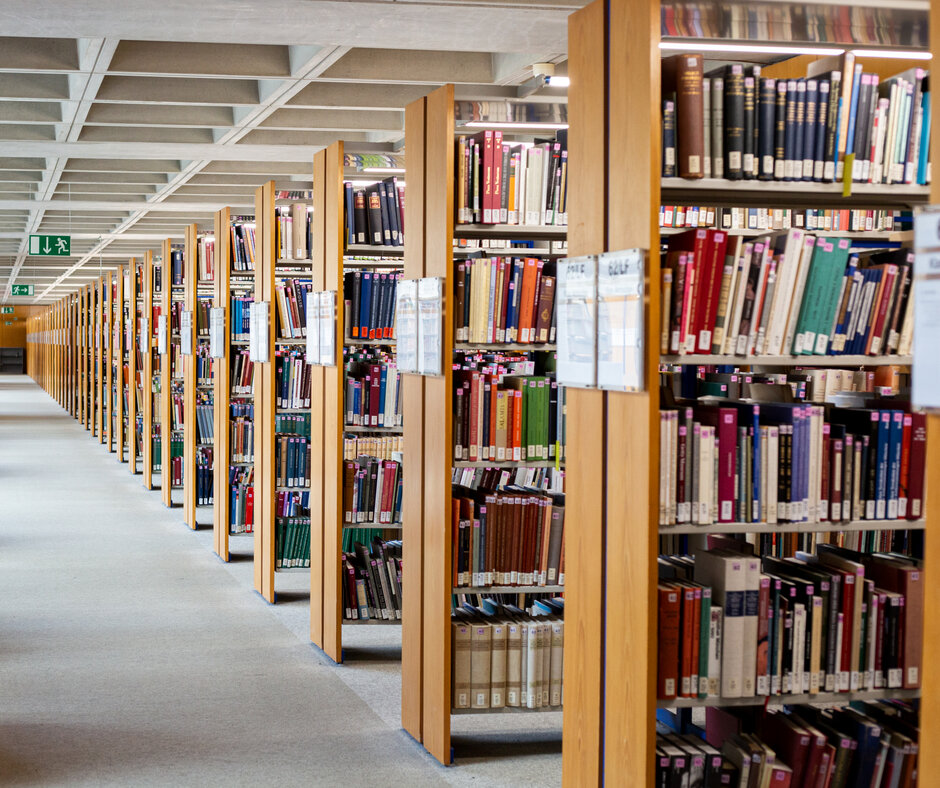 A long, bright corridor, with wooden shelves filled with books stretching to the horizon.