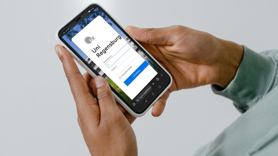 Two hands hold a smartphone on which a login page of the University of Regensburg can be seen.