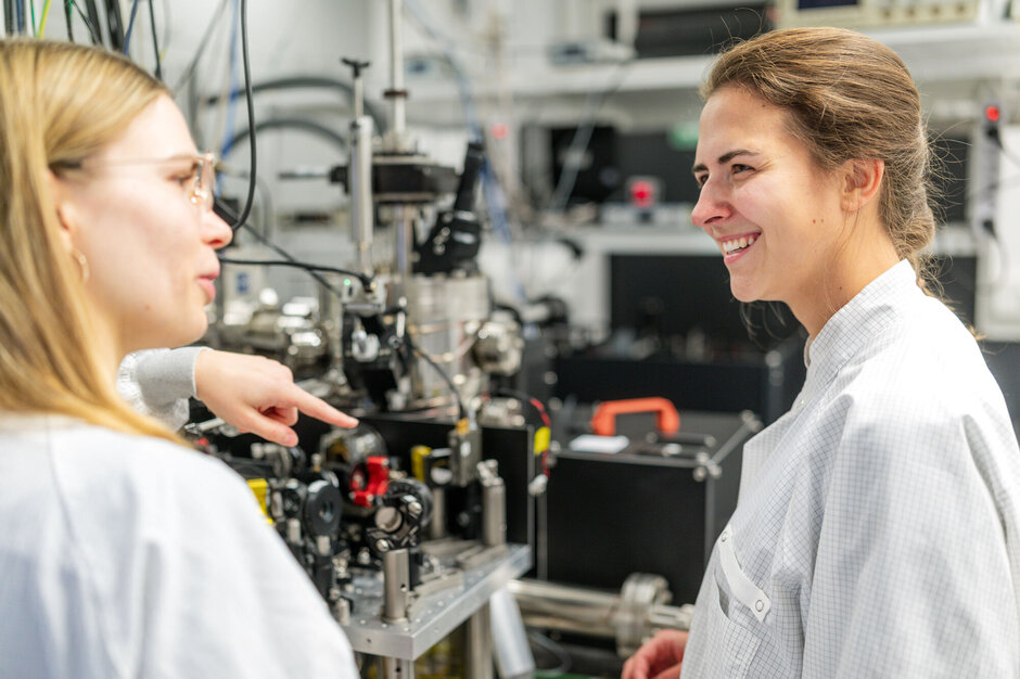 Zwei Frauen an Großgerät der Physik.