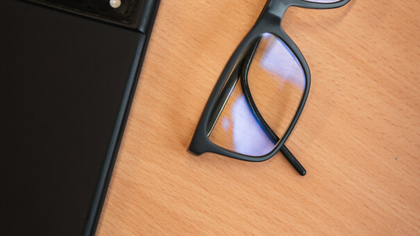 Eine Brille und ein Smartphone liegen auf einem Tisch