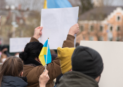 Eine Menschenmenge von hinten mit ukrainischen Flaggen und Protest-Schildern.