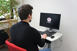 Mann sitzt vor einem Computer Bildschirm.