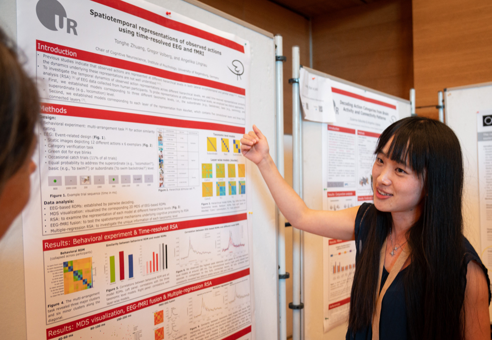 Eine junge Frau erläutert ein wissenschaftliches Plakat.