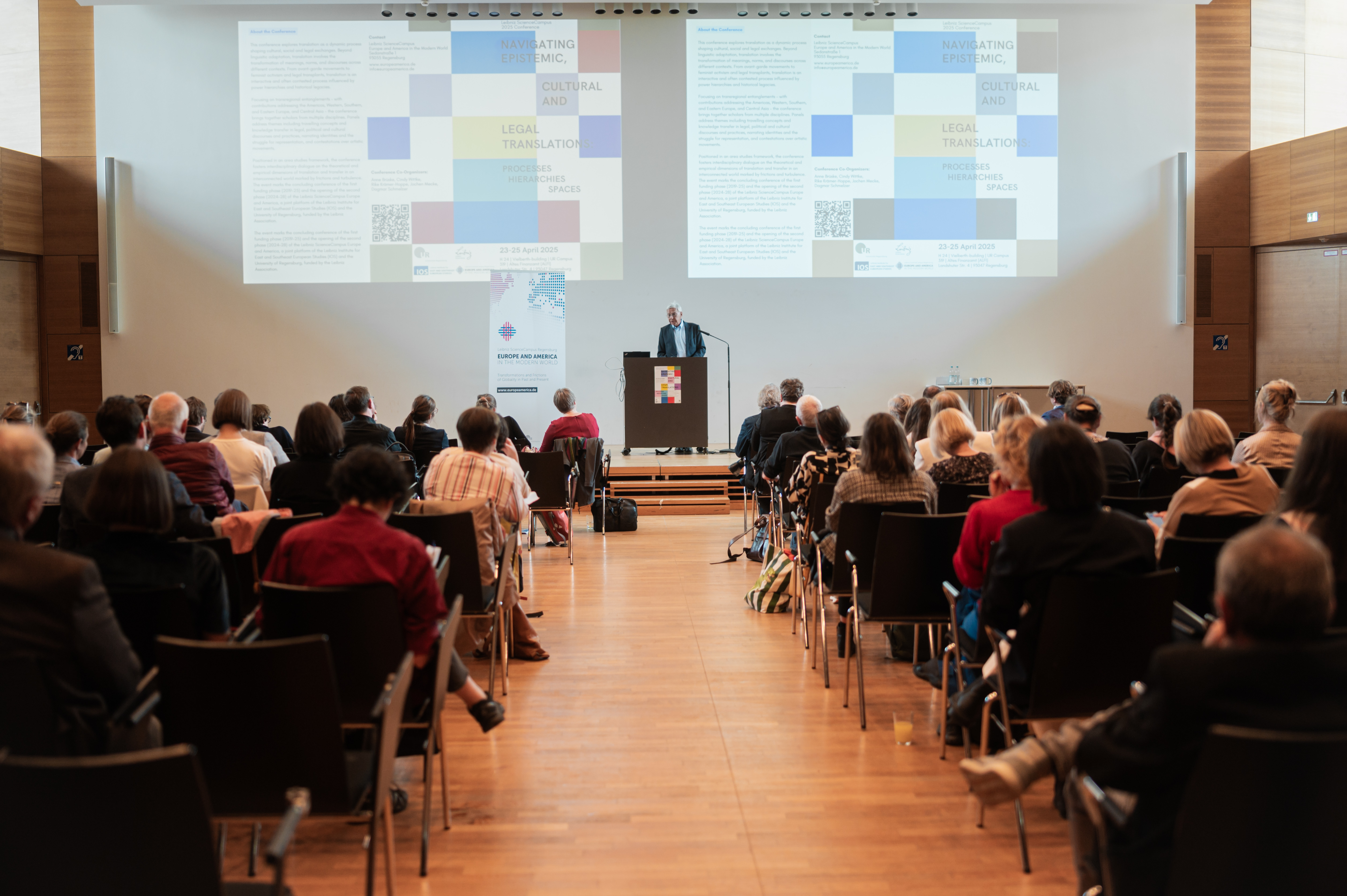 In einem Hörsaal sieht man viele Menschen von hinten sitzen, die einem Herrn beim Vortrag lauschen. (opens enlarged image)